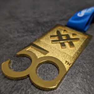 medaglia personalizzata marcialonga in metallo a rilievo 2D senza smalti finitura oro con effetto lente e nastro personalizzato in sublimazione vista laterale