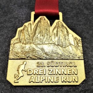 customised Drei Zinnen Alpine Run metal medal in 3D relief with satin gold finish and personalised sublimation ribbon