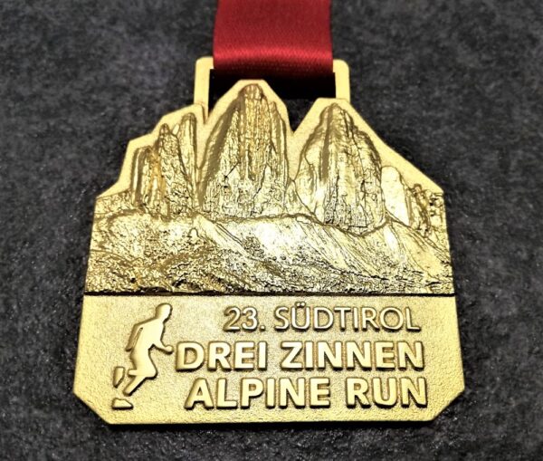 customised Drei Zinnen Alpine Run metal medal in 3D relief with satin gold finish and personalised sublimation ribbon