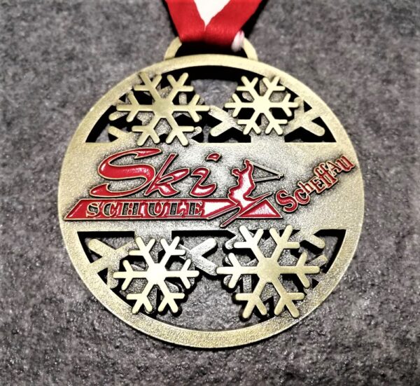 customised Ski Schule Scheffau medal in 2D relief metal with openwork enamel antique bronze finish with red-white ribbon