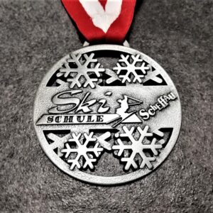 Ski Schule Scheffau customised medal in embossed 2D perforated metal with antique silver finish with red-white ribbon