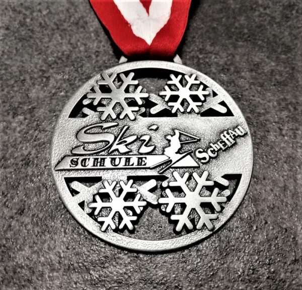 Ski Schule Scheffau customised medal in embossed 2D perforated metal with antique silver finish with red-white ribbon