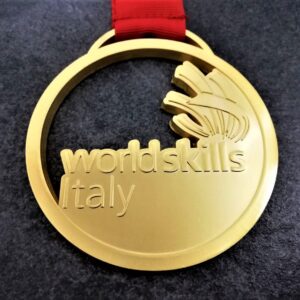customised World Skills Italy medal in embossed 2D perforated metal with satin gold finish with customised silk-screen printed ribbon