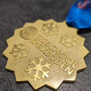 custom skischool speikboden 2D embossed medal without enamel polished and satin gold finish with personalized sublimation ribbon side view