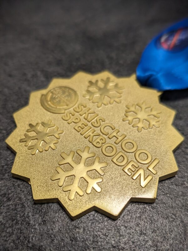 custom skischool speikboden 2D embossed medal without enamel polished and satin gold finish with personalized sublimation ribbon side view