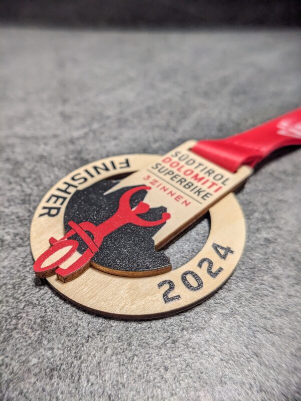 custom südtirol dolomiti superbike medal made of natural wood laser cut and uv printed with stacked layers with personalized sublimation ribbon side view